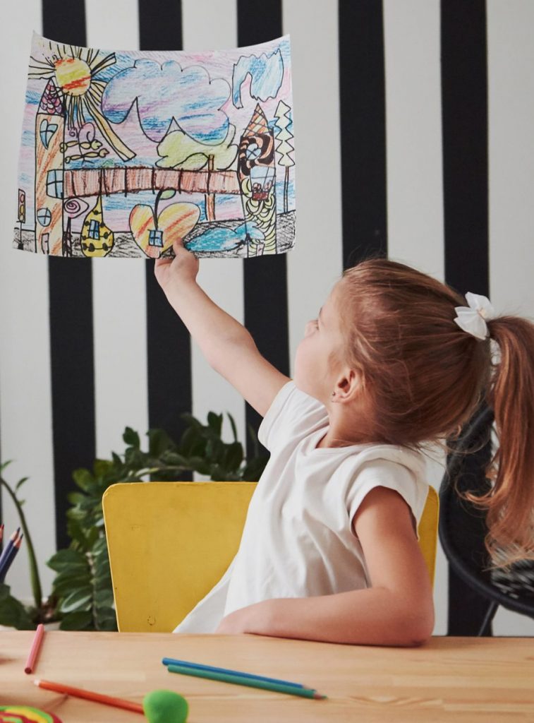 Child pointing to her artwork